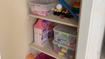 A storage area with shelves containing toys, a plastic container, and a toy car.