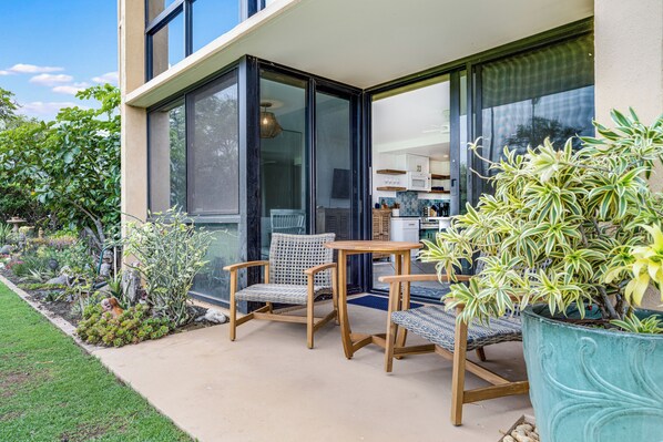 Une terrasse extérieure avec un ensemble de mobilier de jardin et un pot de fleurs.
