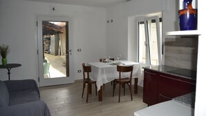 A dining area with a table set for four, wooden chairs, a white tablecloth, and a view through a glass door to an outdoor patio. - Adriana House ground floor with enchanting lake view (Bee)