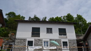 A two-story building with a stone facade, two windows with shutters, and a balcony with a railing. - Adriana House ground floor with enchanting lake view (Bee)