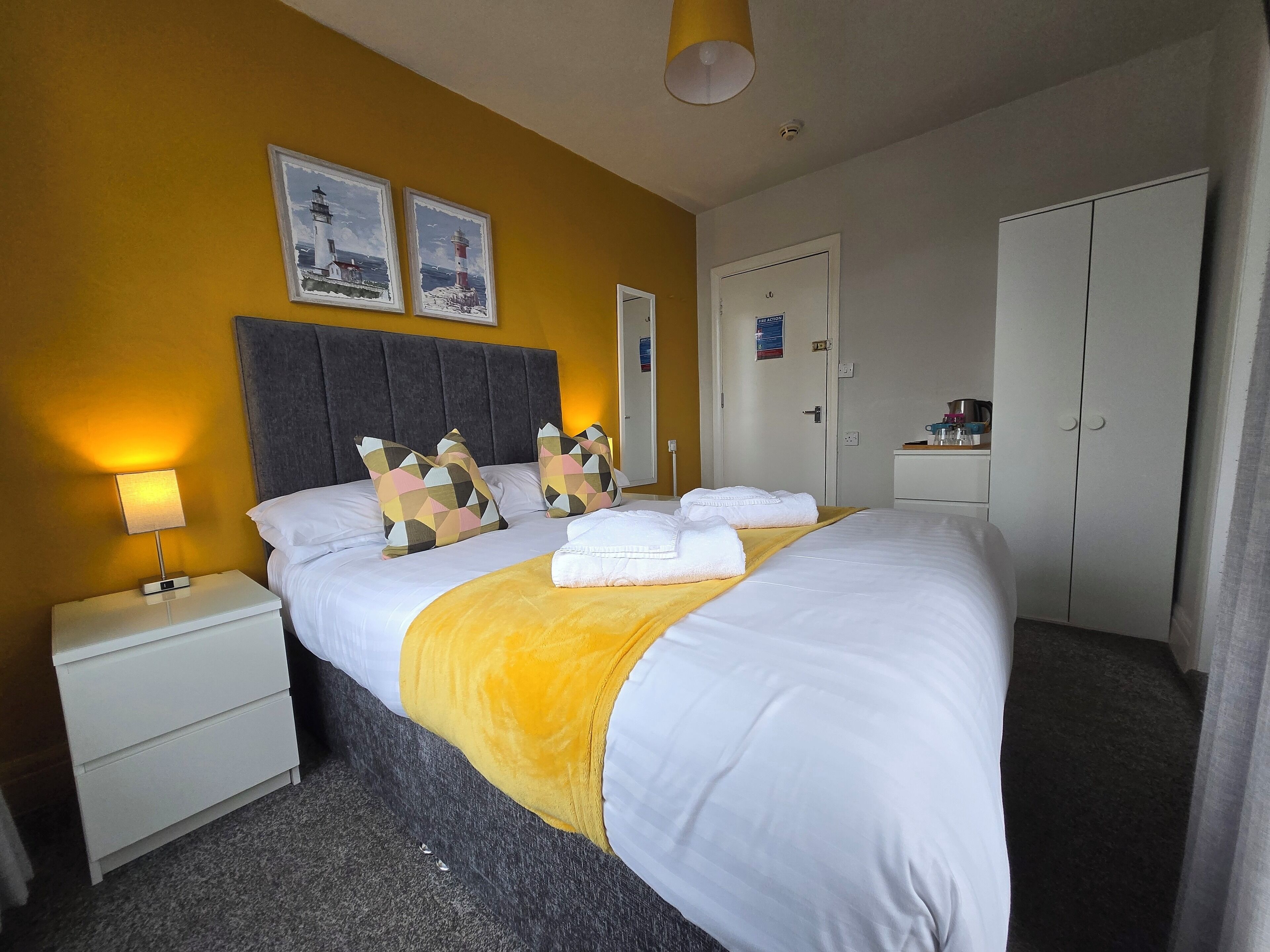 A hotel room with a bed, nightstand, and wardrobe.