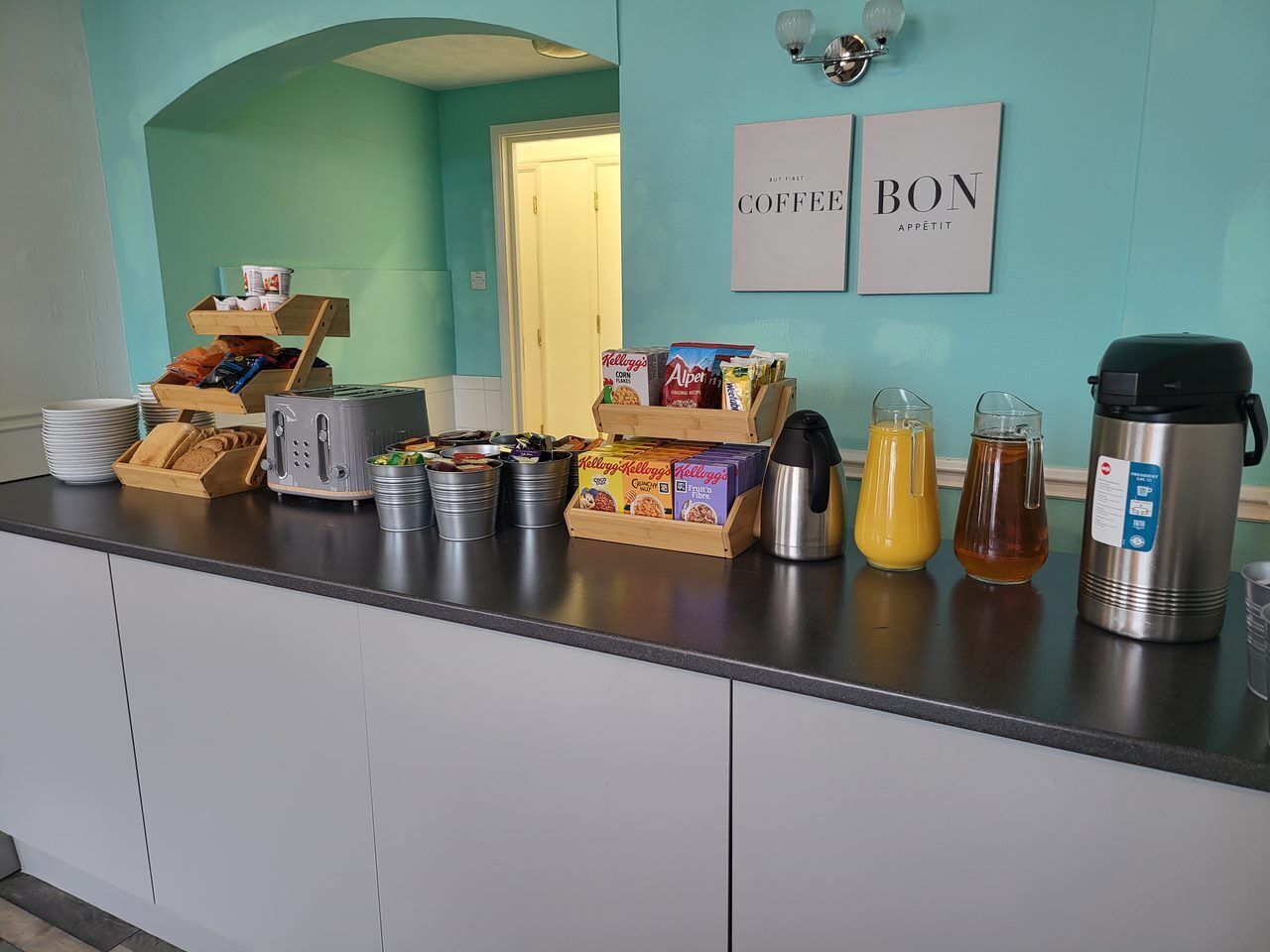 A breakfast bar with various food items, a coffee maker, and a kettle.