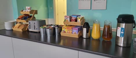 A breakfast bar with various food items, a coffee maker, and a kettle.