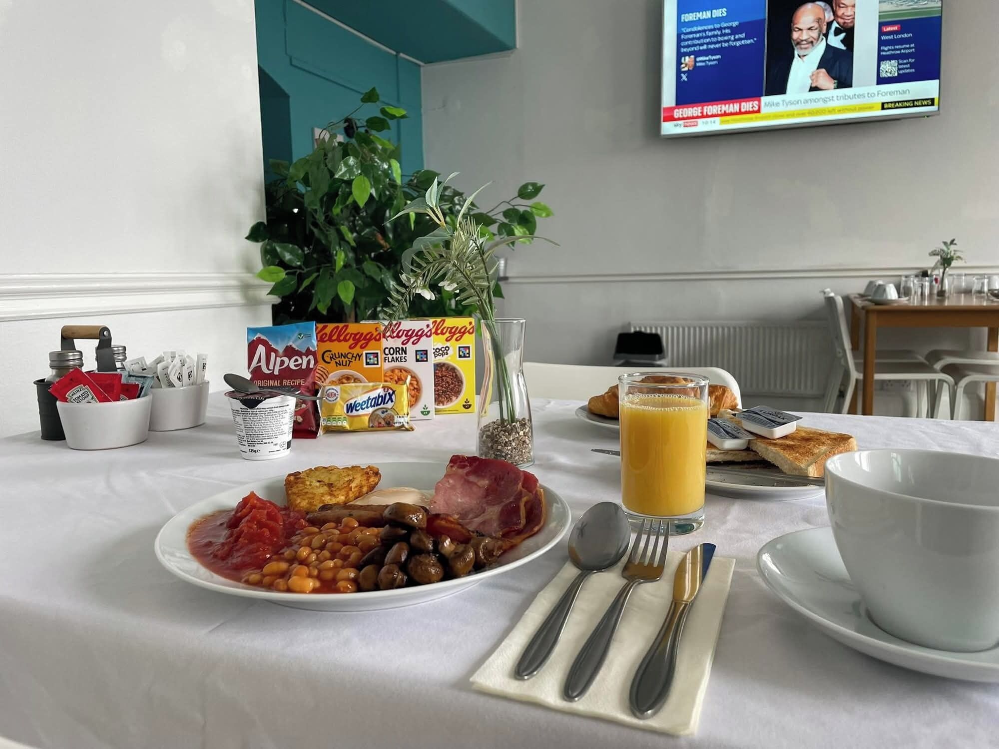 Une table de petit-déjeuner avec une assiette de haricots, des toasts et un verre de jus d’orange.