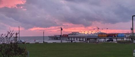 A pier extending into the water with a sunset in the background.