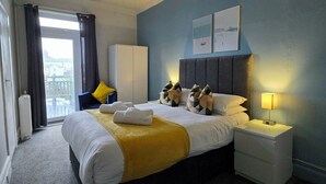 A hotel room with a large bed, a wardrobe, a bedside table, and a view of the outside. - Beach Hotel Torbay (Paignton)