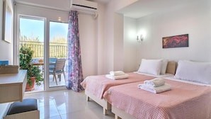 A bedroom with two beds, a desk, and a balcony with a chair and table. - Best Family Friendly Villa Near Lake Kournas (Apokoronas)