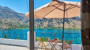 A balcony with a table and chairs, overlooking a lake and mountains. - Gorgeous Lake Kournas Villa Brand New Private Pool (Apokoronas)