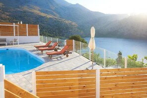 Un espace piscine avec des chaises longues et une vue sur un lac et des montagnes.