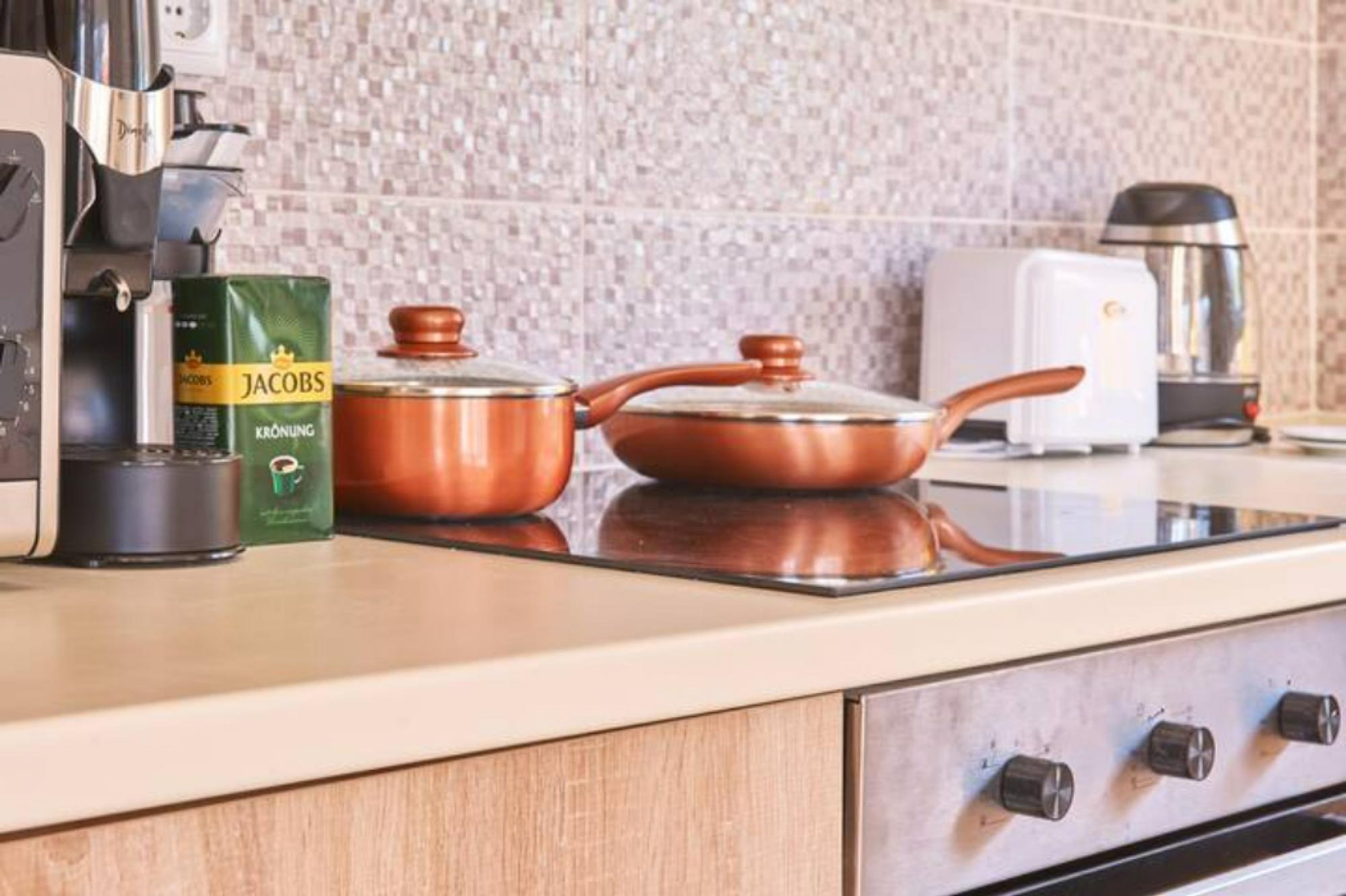 Una cocina con cafetera, hervidor y una caja de café Jacobs Krönung.