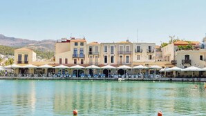 A waterfront hotel with multiple balconies, outdoor seating, and a clear view of the water. - Stunning Lake Kournas Retreat 2 New Private Pool (Apokoronas)