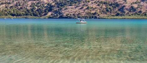 Um barco em um lago calmo com paisagem montanhosa ao fundo.