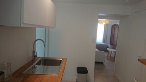 Una cucina compatta con lavello in acciaio inossidabile, piano di lavoro in legno e un piccolo sgabello.