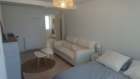 A modern, minimalist bedroom with a bed, a sofa, and a small table.