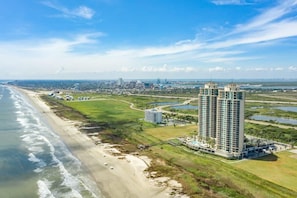 Un hotel costero con varios edificios de gran altura, una playa y un campo de golf.
