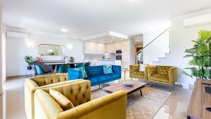 A modern living room with a sofa set, a coffee table, and a dining area with chairs and a table. - Casa Malhotra at Boa Vista Golf Resort, Bayview Village (Lagos)