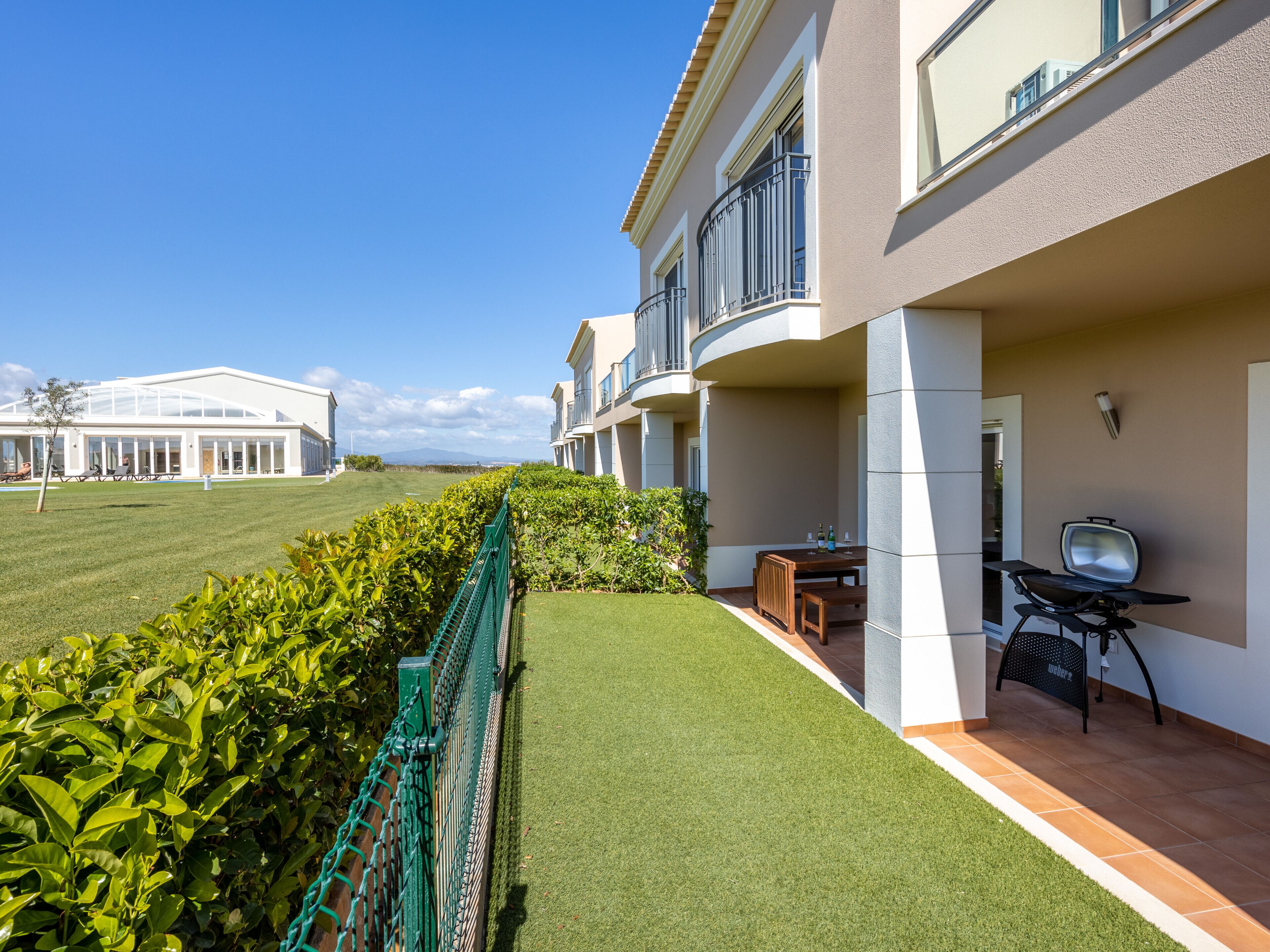 Un hôtel moderne doté d’une pelouse bien entretenue, d’un espace barbecue et offrant une vue sur un bâtiment situé au loin.