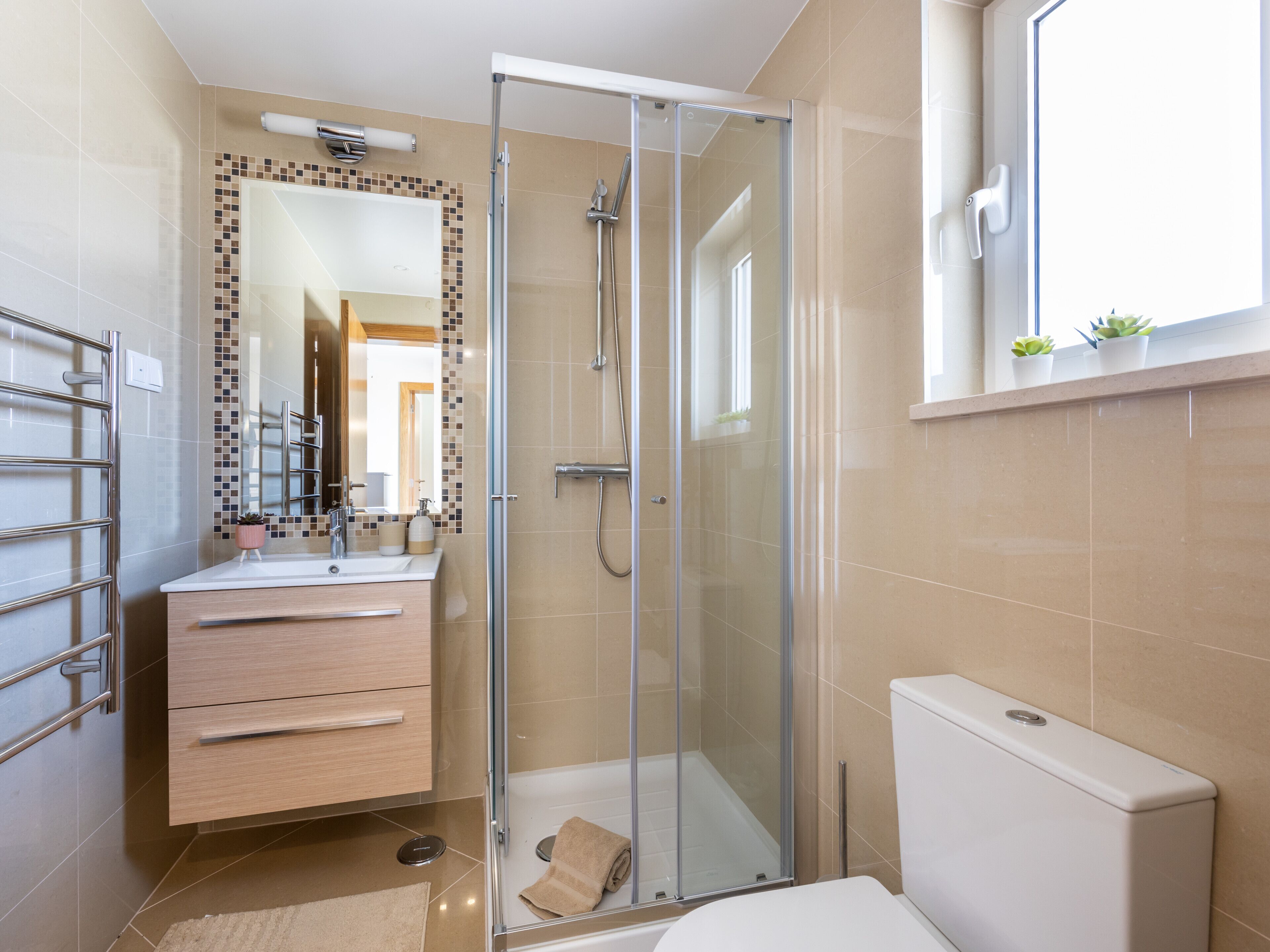 A modern bathroom with a glass-enclosed shower, a sink with a mirror, and a toilet.
