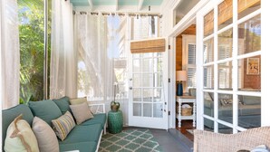 Une pièce chaleureuse avec un canapé vert, un tapis à motifs et un fauteuil en osier.