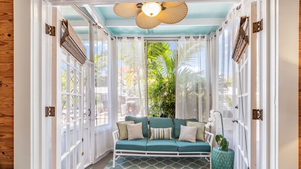 Une pièce chaleureuse avec un canapé vert, un tapis à motifs et un ventilateur de plafond.