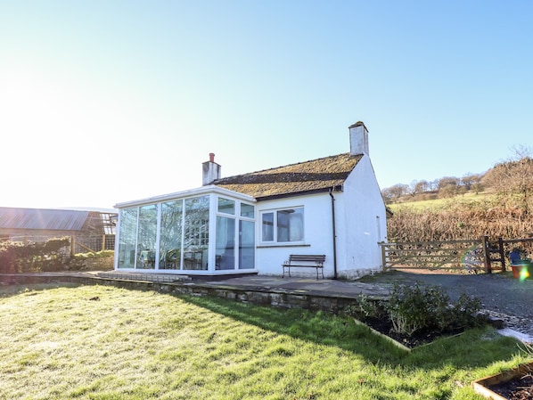 A white house with a glass conservatory, a bench, and a garden. - Ty Twmp / Tump Cottage (Brecon)