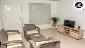 Un salón amueblado con un conjunto de sofás, un televisor y una planta en maceta.