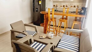 Un comedor acogedor con mobiliario de mimbre y cojines a rayas, una cocina moderna con armarios de madera y un refrigerador empotrado.