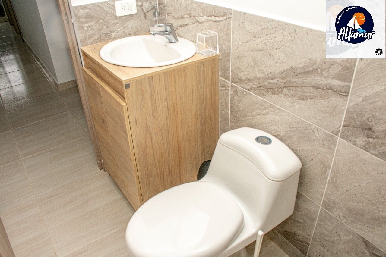 Une salle de bain moderne avec un meuble-lavabo en bois, un lavabo blanc et des toilettes.