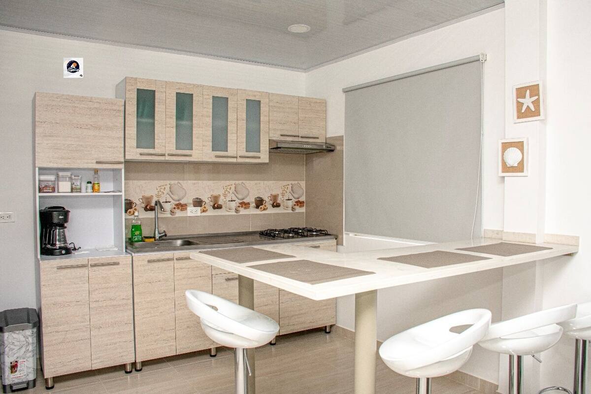 A modern kitchen with a central island, white bar stools, and a coffee machine.