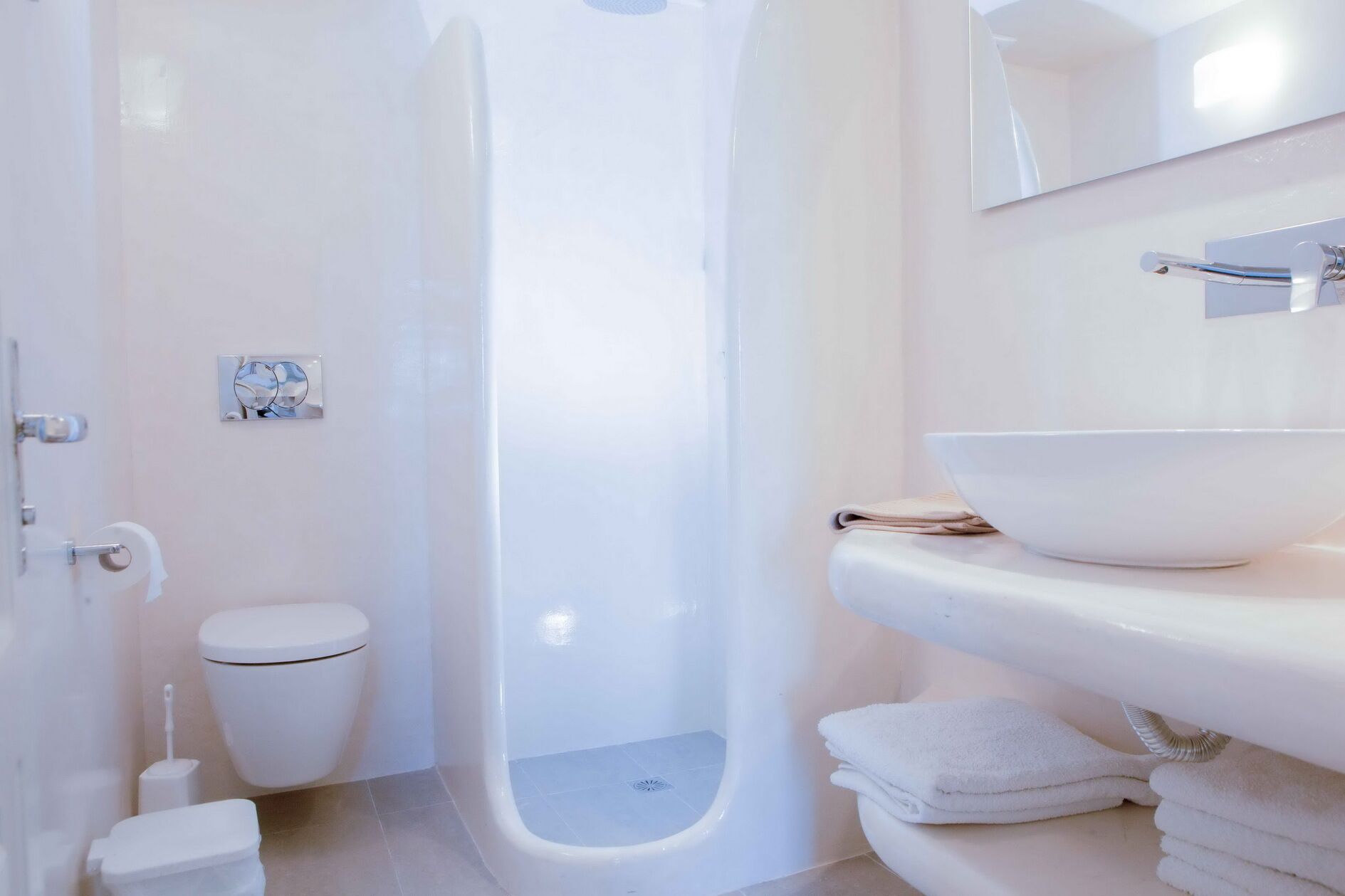 A modern bathroom with a white toilet, a shower, and a sink with a large bowl.