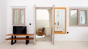 A modern living room with a TV, wooden bench, and open sliding doors leading to a bathroom.