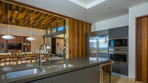 Una cucina moderna con isola centrale, elettrodomestici in acciaio inossidabile e soffitto in legno.