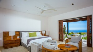 Camera d'hotel moderna con un letto, due poltrone, un tavolino da caffè e vista sull'oceano.