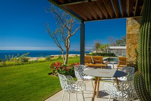 Une terrasse avec une table et des chaises, une piscine et une vue sur l’océan.