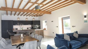 A modern kitchen with dark cabinets, a wooden dining table, and a blue sofa.
