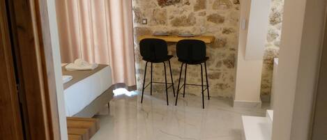 A modern interior with a stone wall, a dining area with two chairs, and a staircase leading to a lower level.