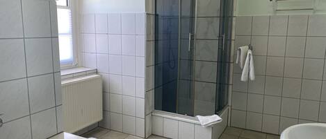 A bathroom with a bathtub, a glass-enclosed shower, and a sink.