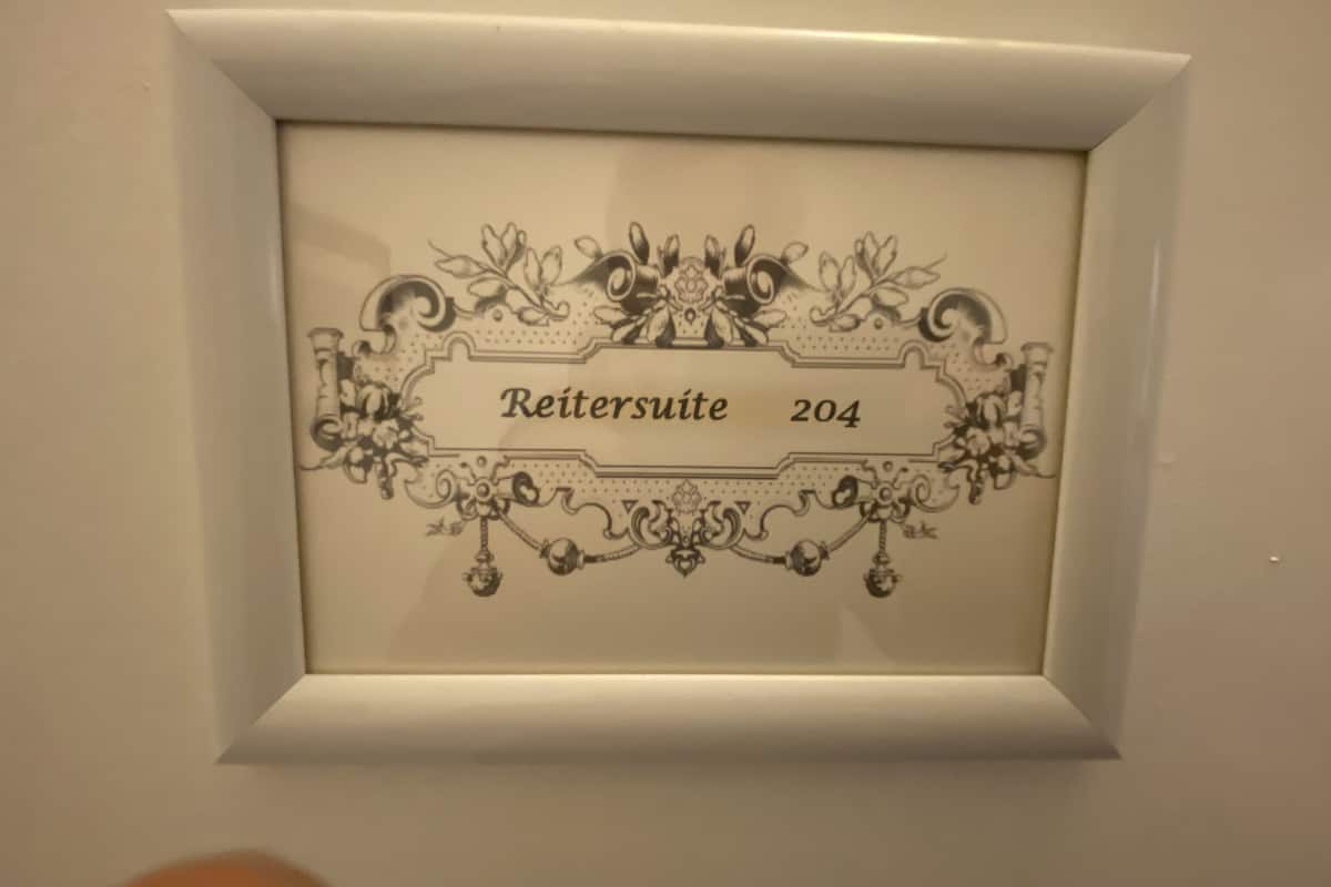 A framed sign with the text "Reitersuite 204" surrounded by ornate floral designs.