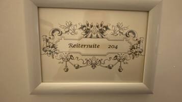 A framed sign with the text "Reitersuite 204" surrounded by ornate floral designs.