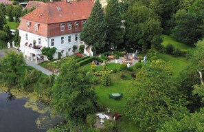 A large white building with a red-tiled roof, surrounded by lush greenery and a pond. - Jagdschloss Lalendorf (Lalendorf)