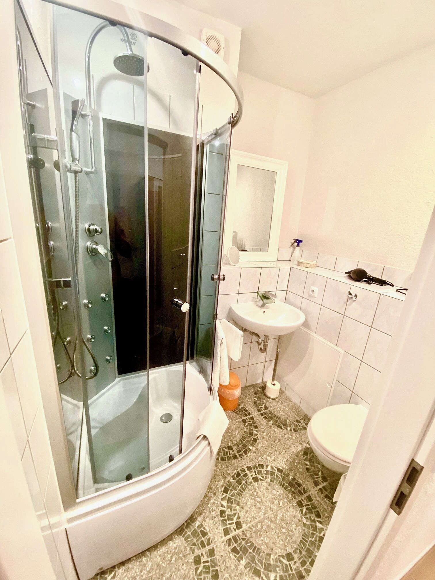 A bathroom with a glass-enclosed shower, a sink, and a toilet.