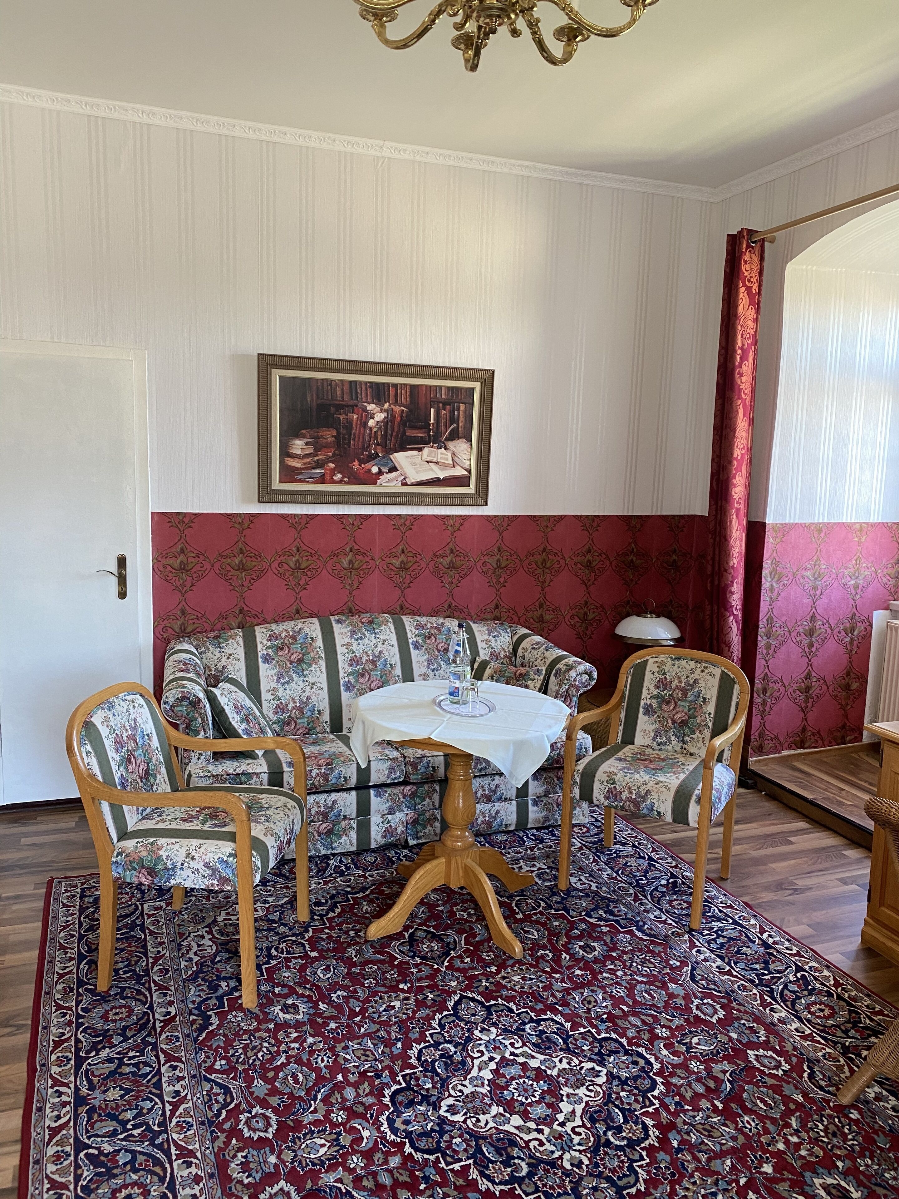 Ein Zimmer mit einer gepolsterten Couch, einem kleinen runden Tisch und einem gemusterten Teppich.