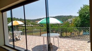 Un balcon donnant sur un paysage verdoyant, avec deux parasols et une table.