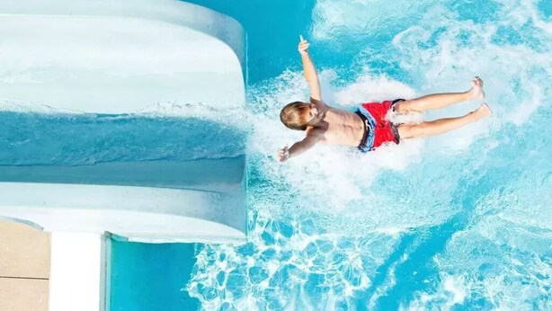 Un enfant dans une piscine avec un toboggan aquatique.