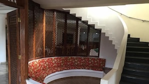 Un escalier en colimaçon avec une rampe en bois et un banc rouge orné de motifs floraux.