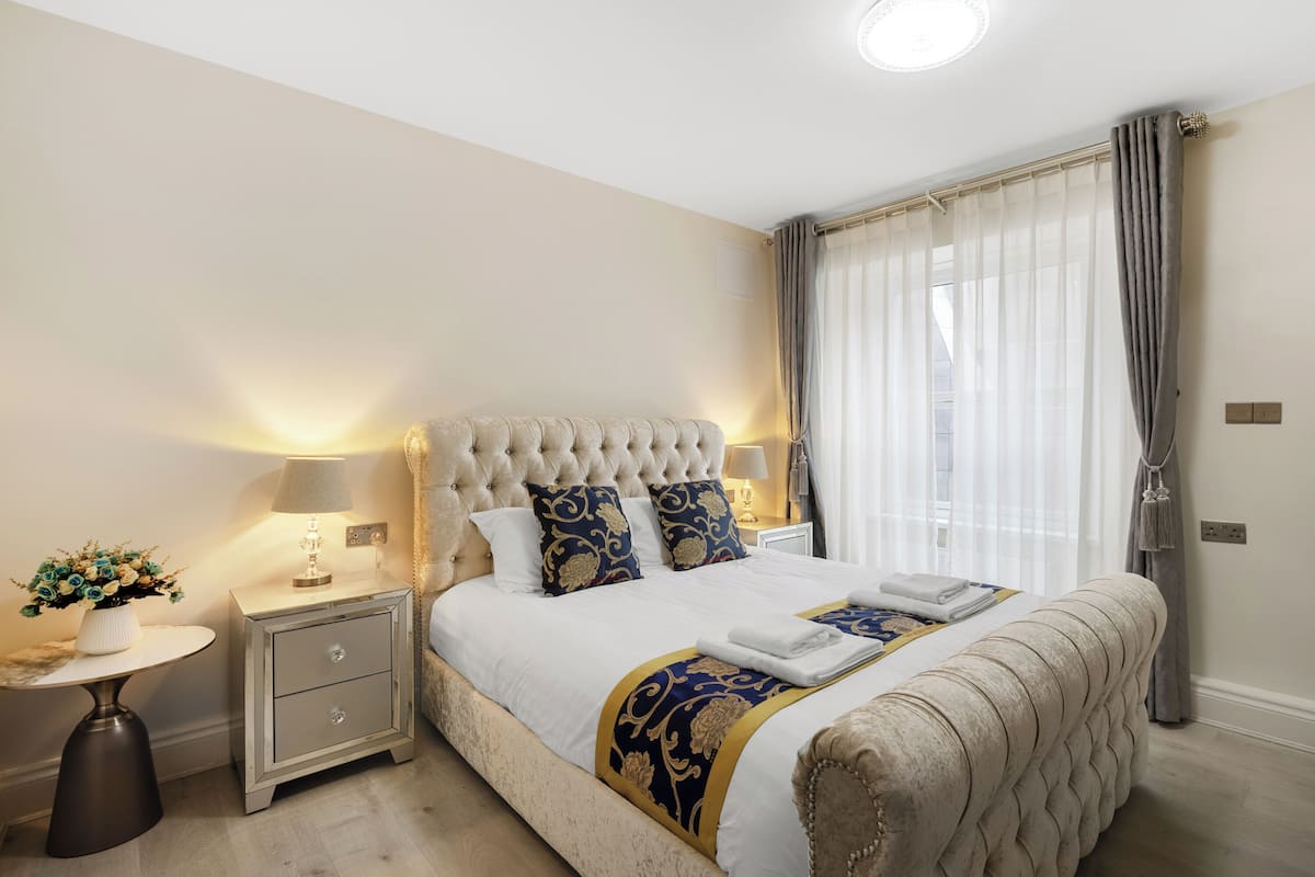 Une chambre à coucher bien rangée, avec un grand lit, des tables de chevet et une petite table de nuit.
