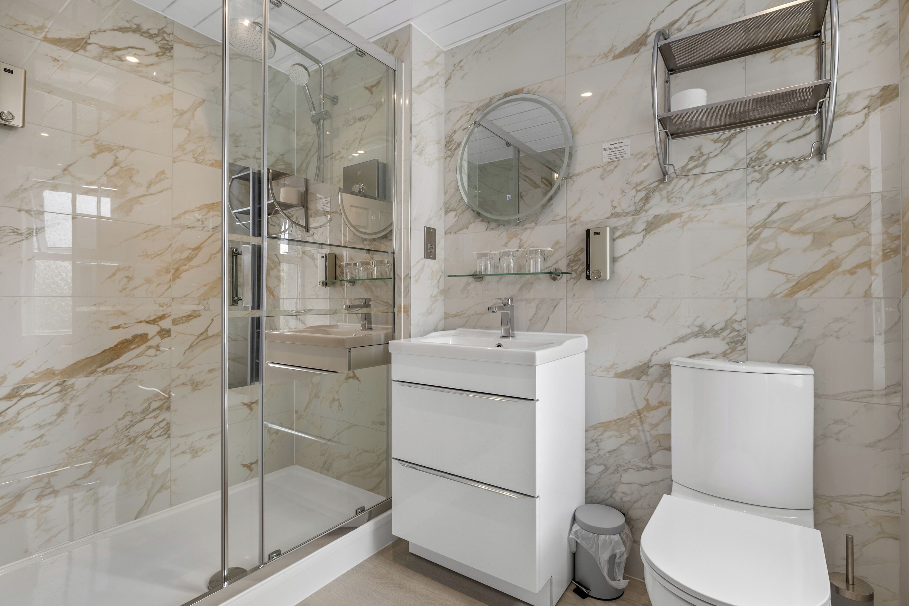 Une salle de bain moderne avec une douche à parois de verre, un lavabo blanc et des toilettes.