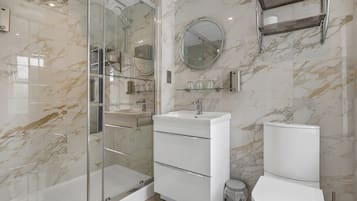 Une salle de bain moderne avec une douche à parois de verre, un lavabo blanc et des toilettes.