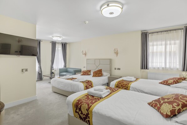 A hotel room with three beds, a TV, a sofa, and a large window with curtains. - The Drake Hotel Plymouth (Plymouth)