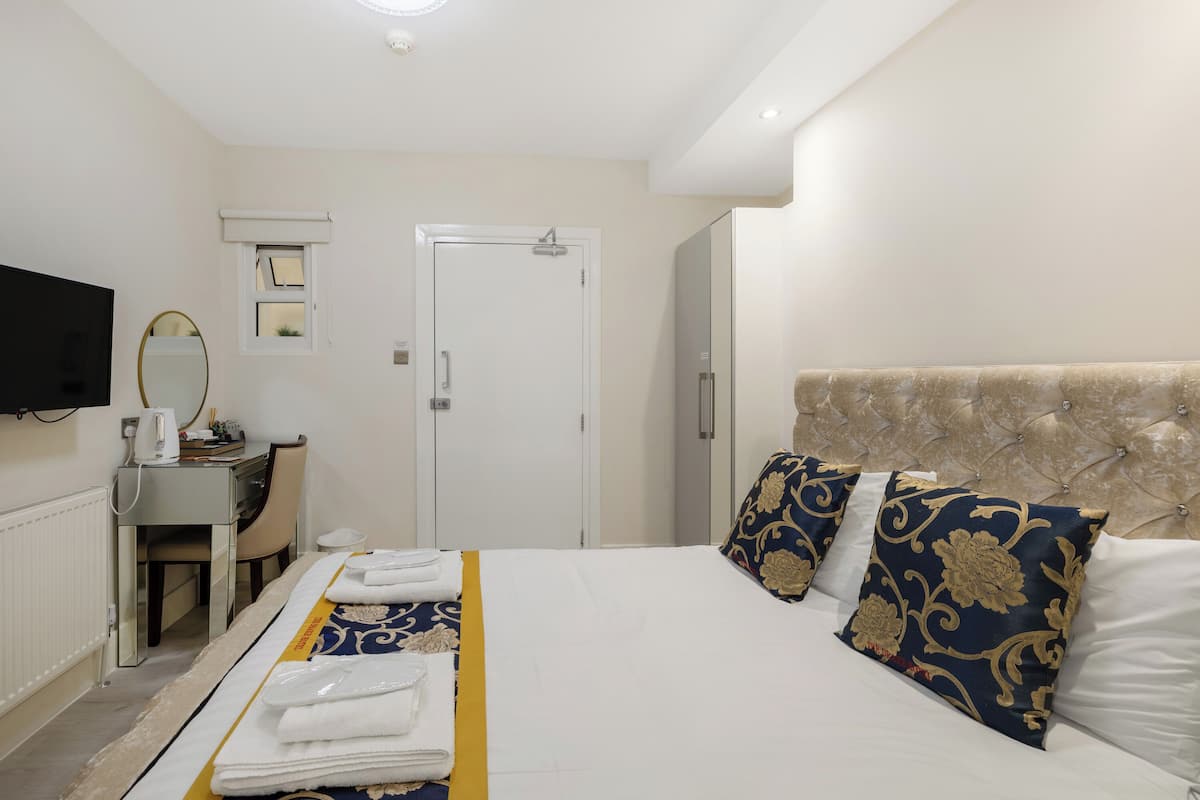Une chambre d’hôtel avec un lit, un bureau, une chaise, une télévision et une porte.